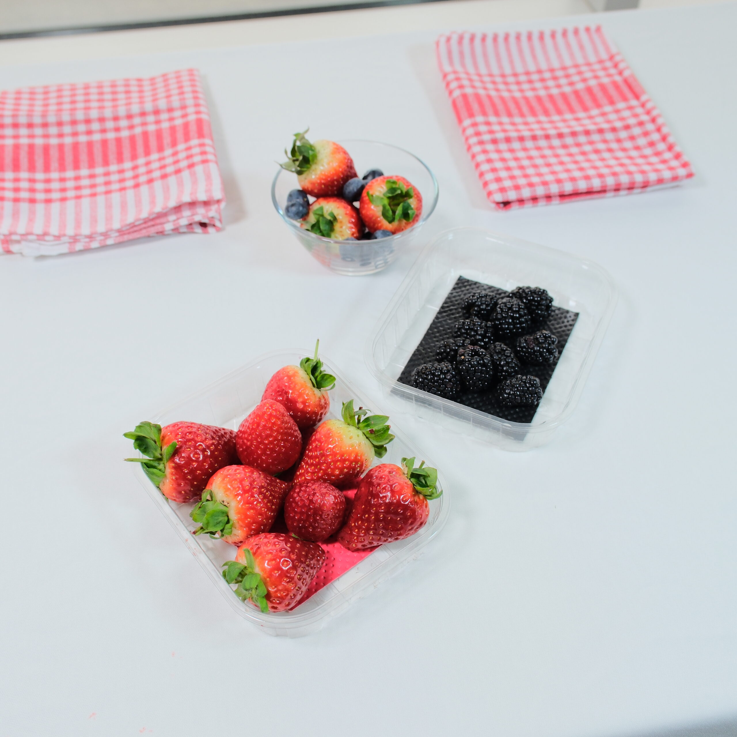 Fresh strawberries and blackberries packed in trays with absorbent pads