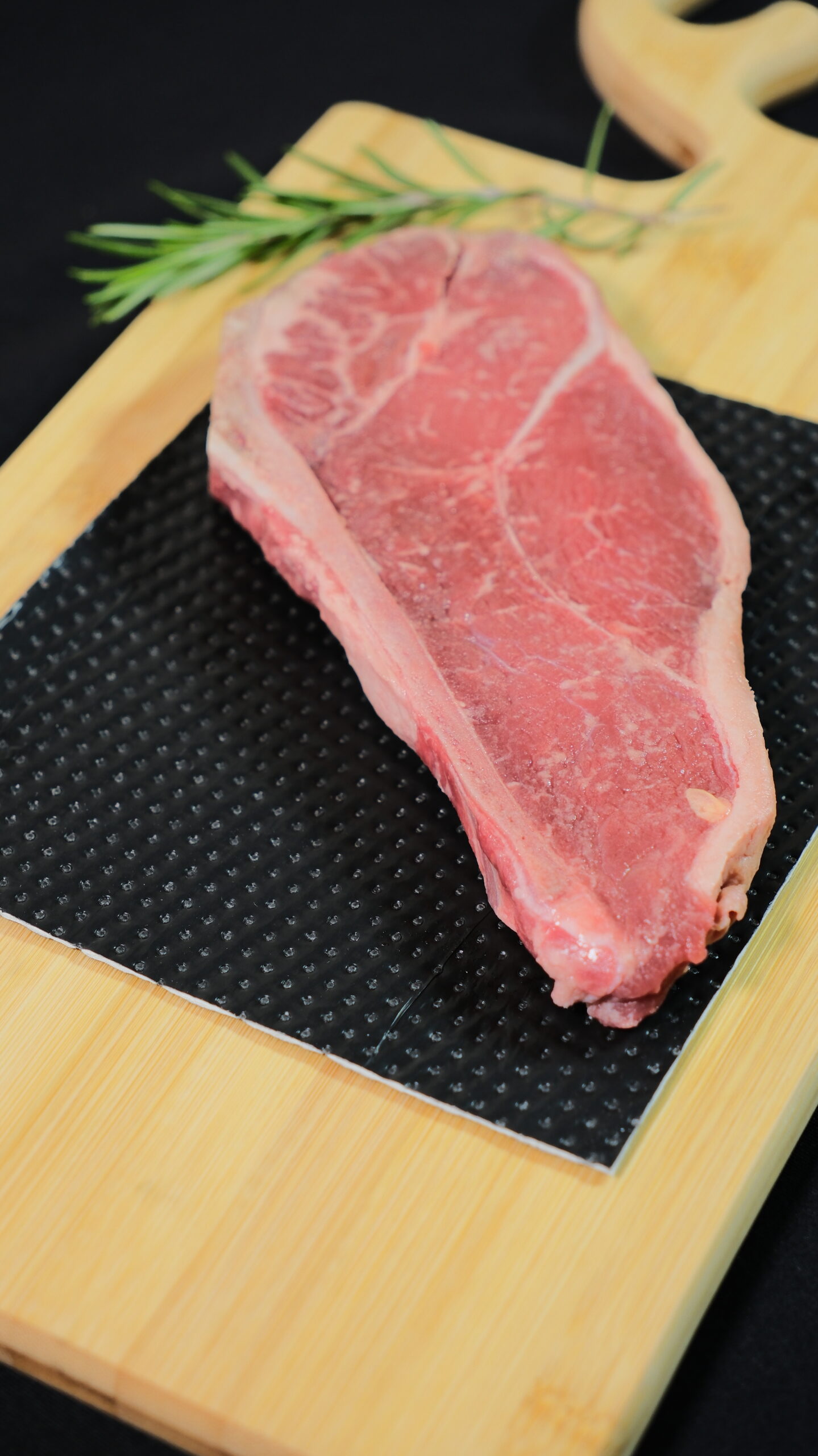 Raw beef steak resting on a black absorbent pad